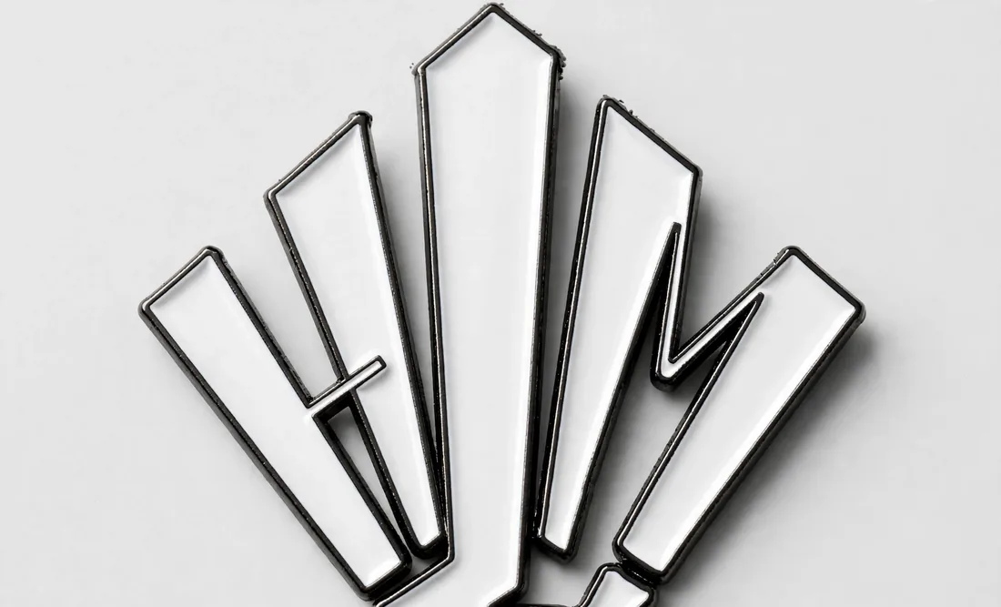 Pin's noir mat — Version sombre, logo en relief.